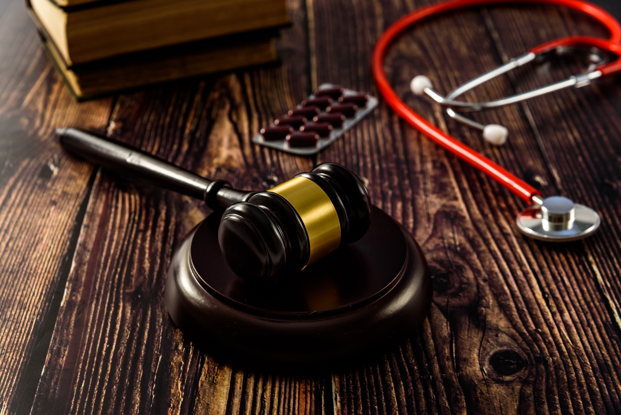 Medical malpractice and errors makes doctors and patients go to court, gavel on legal books.