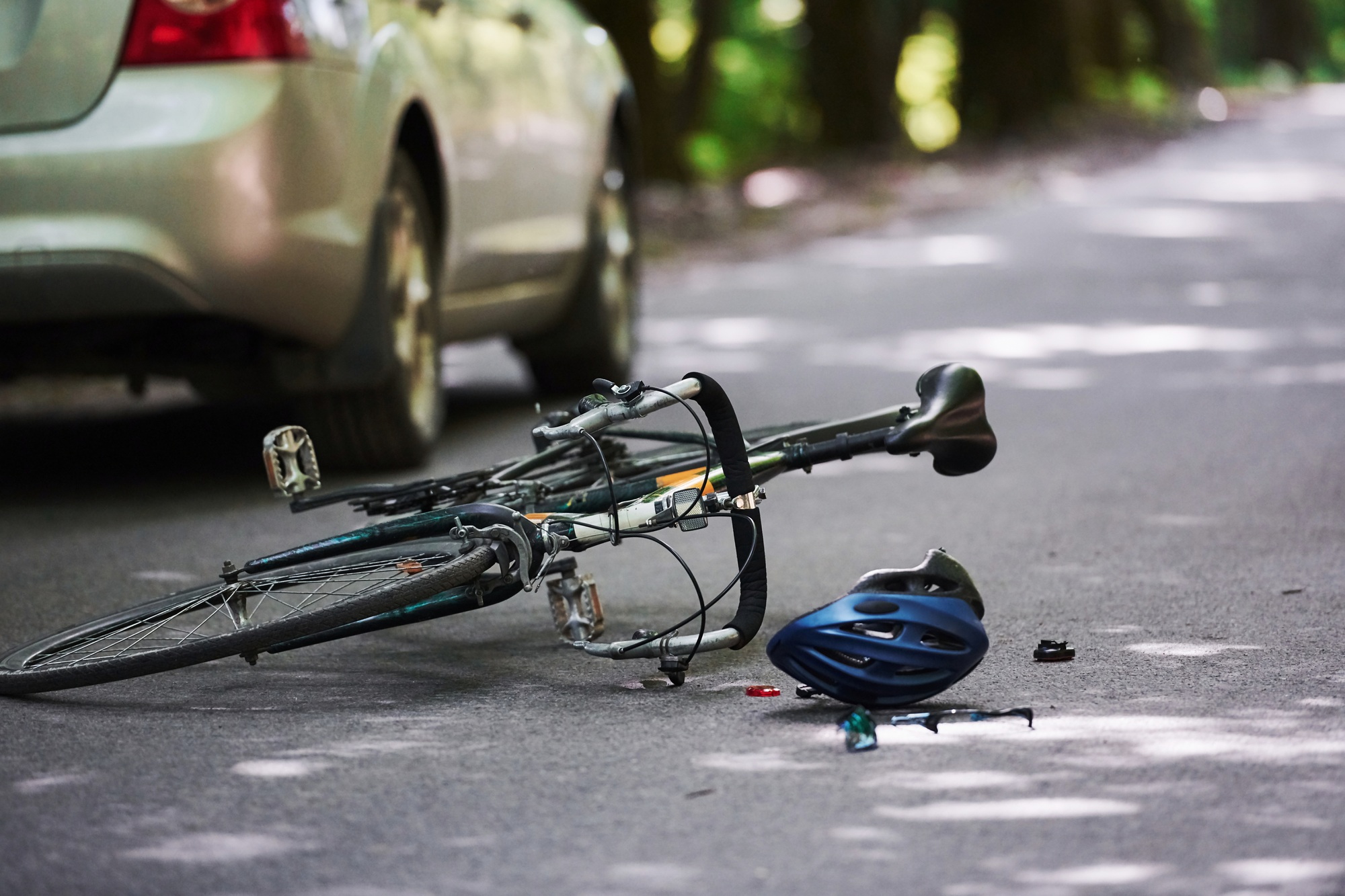 The place of the break. Bicycle and silver colored car accident on the road at forest at daytime